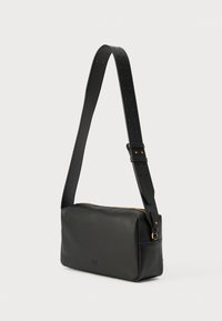 Μαύρη δερμάτινη τσάντα ώμου με ρυθμιζόμενο ιμάντα, ορθογώνιο σχήμα, χρυσό φερμουάρ και ομαλή υφή. Μινιμαλιστικός σχεδιασμός με διακριτικό λογότυπο.