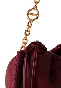 Burgunderfarbene Lederhandtasche mit einem goldenen Kettenhenkel. Verfügt über einen strukturierten Bereich am Tragegurt und ein rundes Zubehörteil.