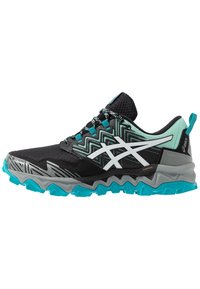 Chaussure de trail running avec un dessus noir à motif géométrique et des accents blancs, semelle turquoise, et intermédiaire texturé pour l'adhérence et le soutien.