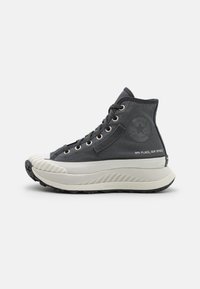 Hoge sneakers van donkergrijs stof met een witte zool. Heeft een textuur op de neus, metalen veterogen en een logo aan de zijkant.