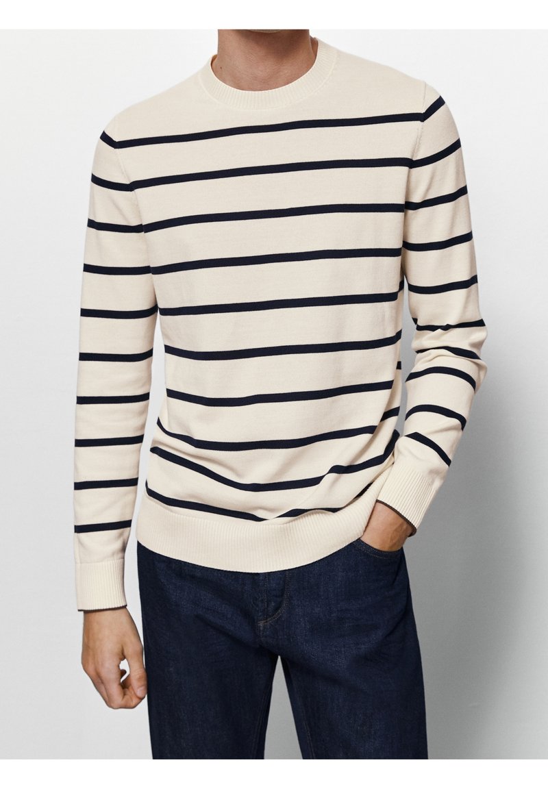 Cremfarbener Pullover mit navyblauen horizontalen Streifen, Rundhalsausschnitt, gerippten Bündchen und Saum, kombiniert mit dunkelblauen Denim-Jeans. Weicher, leichter Strickstoff.