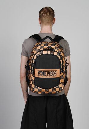 Mochila a rayas en negro y naranja con logotipo. Cuenta con correas ajustables, un gran bolsillo frontal y tela texturizada con detalles gráficos.