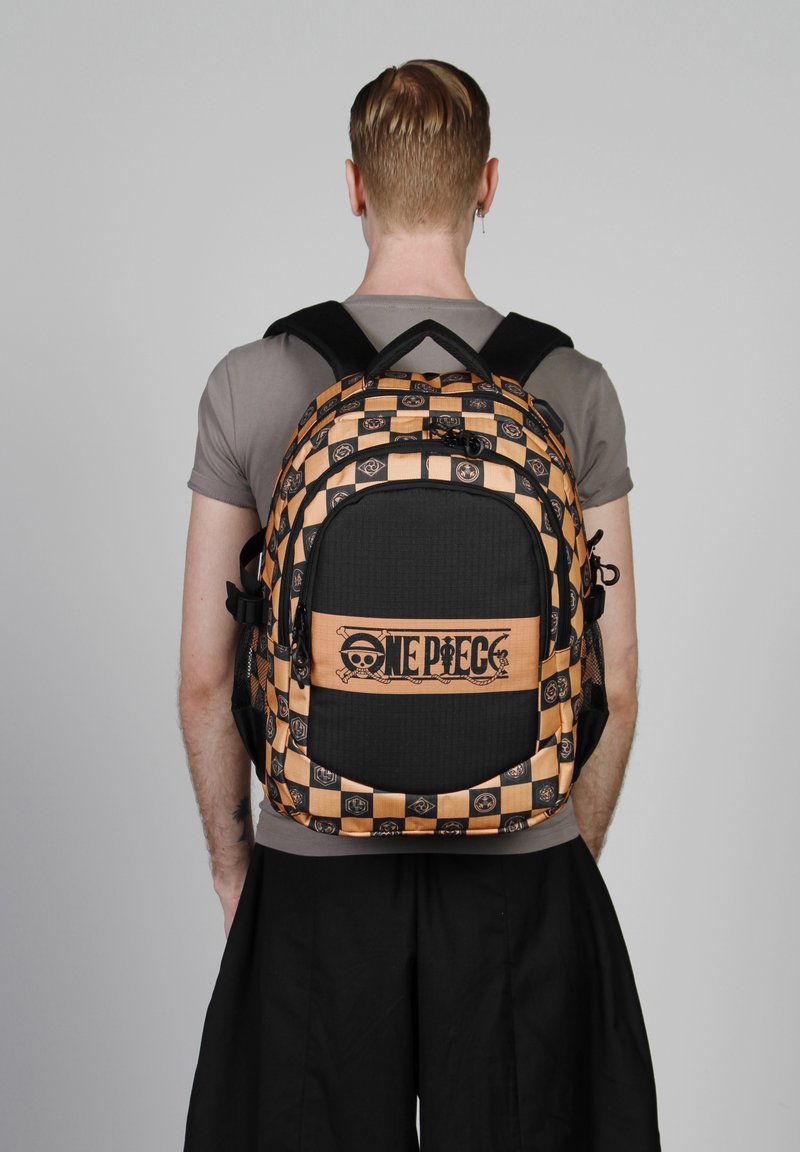 Mochila a rayas en negro y naranja con logotipo. Cuenta con correas ajustables, un gran bolsillo frontal y tela texturizada con detalles gráficos.