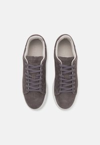 Gray suede sneakers with a low-top design, textured surface, gray laces, and white rubber soles. Notable brand lettering on the tongue.