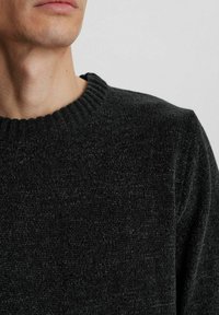 Dunkelgrauer Strickpullover mit strukturierter Oberfläche, mit geripptem Rundhalsausschnitt und weichem Stoff. Nahaufnahme des Brustbereichs.