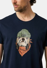 Mörkblå bomulls-t-shirt med en grafisk design av en bulldog som bär en grön mössa och hörlurar, med en detalj av ett orange bandana.