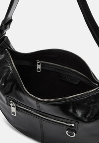 Czarna skórzana torba na ramię o gładkiej teksturze, z zamkami błyskawicznymi w kolorze srebrnym oraz wieloma wewnętrznymi kieszonkami do organizacji.