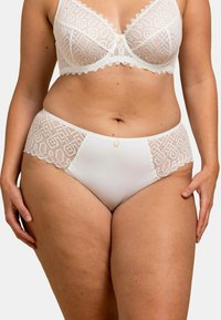 Ensemble de lingerie blanche comprenant un soutien-gorge en dentelle avec des motifs géométriques et une culotte assortie. La culotte possède des panneaux latéraux en dentelle et un bouton décoratif.