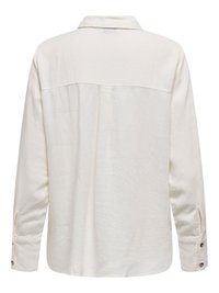 Set bagfra af en langærmet, off-white skjorte med krave, enkelt ryg-plissering og manchetter med knapper.