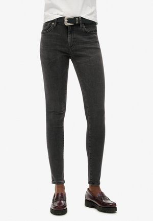 Skinny jeans in donkergrijs denim, met een klassieke vijf-pocket stijl en een zilveren gesp riem. De stof heeft een subtiele textuur.