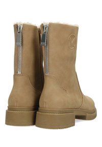 Bruna mockaskinnstövlar till anklarna med silvriga dragkedjor och mjuk foder. Har en gummisula med räfflor och en cirkulär logotyp präglad på sidan.