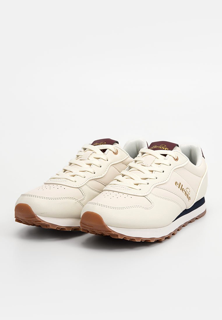 Des chaussures de sport de couleur crème avec une tige synthétique lisse, présentant un accent bleu marine foncé et une semelle extérieure en caoutchouc marron, un design à lacets et un détail de logo.