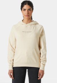 Beige hoodie met een voorzak, met de tekst "HELly HANSEN 1877" in lichtgrijs gedrukt. Zachte stof met ribgebreide boorden en zoom.