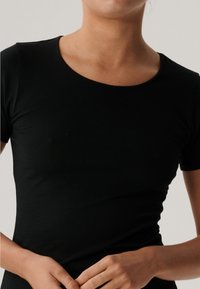 Czarny t-shirt z krótkim rękawem wykonany z gładkiego, elastycznego materiału, z okrągłym dekoltem i dopasowanym krojem, prezentujący prosty, minimalistyczny design.