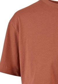 T-shirt kratkih rukava u rustikalnoj narančastoj boji, izrađen od mekanog pamuka. Ima okrugli izrez i minimalne šavove na rukavima.