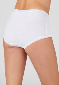 Mutande in cotone bianco con un design a vita alta, decorate con pizzo lungo l'elastico della vita e le aperture delle gambe. Texture liscia e costruzione semplice.