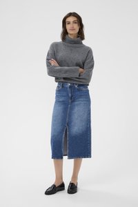 Harmaa slipover, keskikokoinen neule, yhdistettynä siniseen farkku-midi-hameeseen, jossa on edessä halkio. Mustat loafersit täydentävät asua.