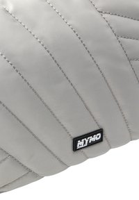 Cuscino grigio imbottito con motivi cuciti e una texture liscia. Presenta un'etichetta nera con testo bianco che riporta la scritta "MYMO."