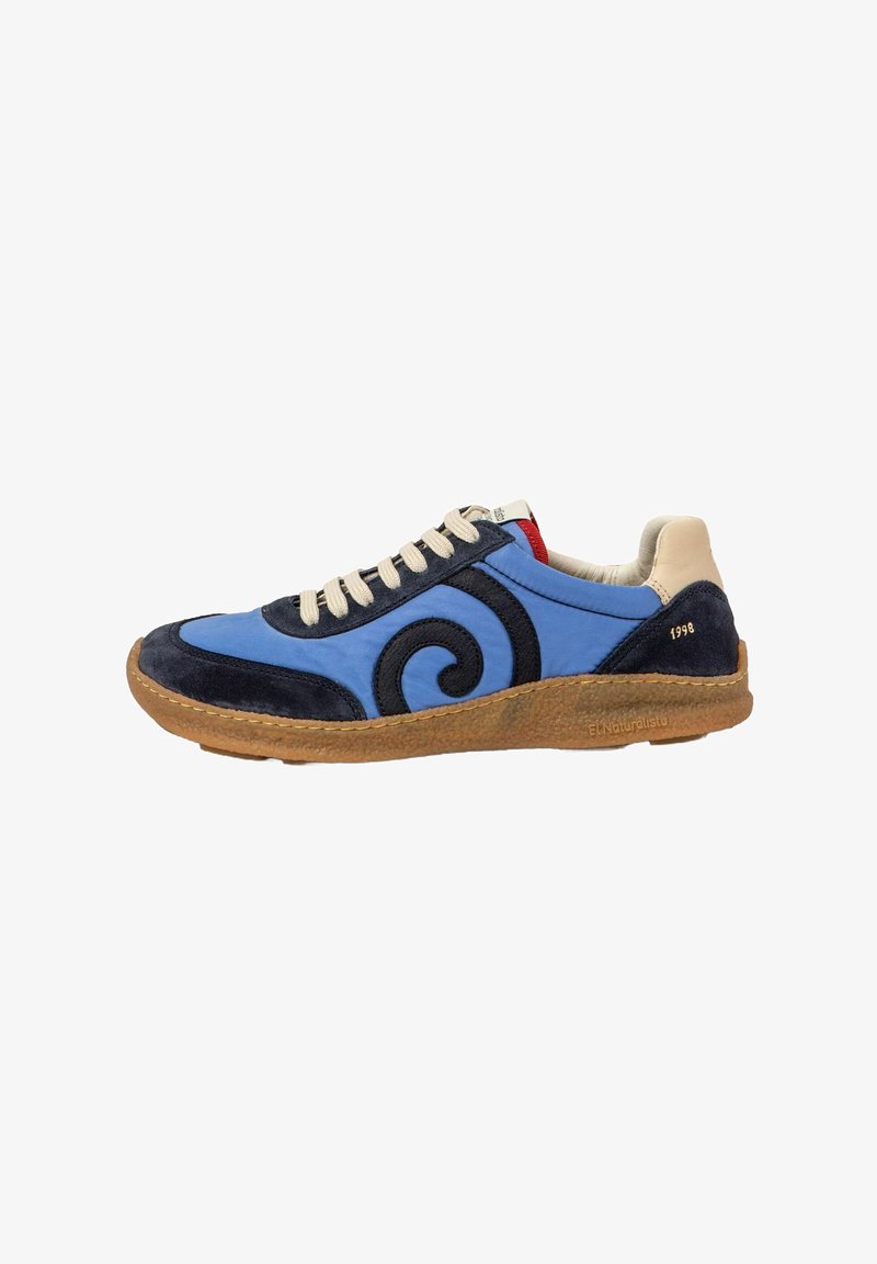 Sneakers bleues et navy avec un talon beige, des lacets blancs, une semelle marron, un design noir en tourbillon sur le côté, et "1998" imprimé sur le talon.