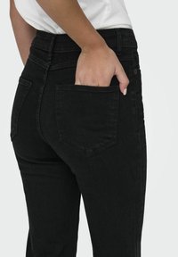 Svarta denimjeans med en åtsittande design, medelhög midja och bakficka. Hand inlagd i den högra bakfickan. Slät textur.