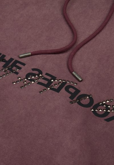 Bordeaux hoodie met een trekkoordsluiting. Bevat zwart bedrukte tekst en metalen studaccenten. Zachte stof met een iets gestructureerd oppervlak.