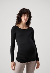 Black long-sleeve maternity top, featuring a round neckline and gathered detailing at the sides. Soft, stretchable fabric complements a fitted shape.