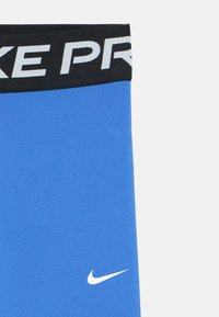 Pantalones cortos deportivos azules con una cinturilla negra que presenta "NIKE PRO" en texto blanco. Incluye un logo de Nike blanco en el lado inferior.