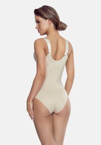 Beżowy body z cienkimi ramiączkami i niskim tyłem. Gładka tekstura, elastyczny materiał i dyskretne szwy. Subtelny połysk na ramiączkach.
