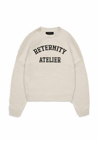 Cream-colored sweater with a round neckline, drop shoulders, and ribbed cuffs. Features black text: “RETERNITY ATELIER” in an arched format.