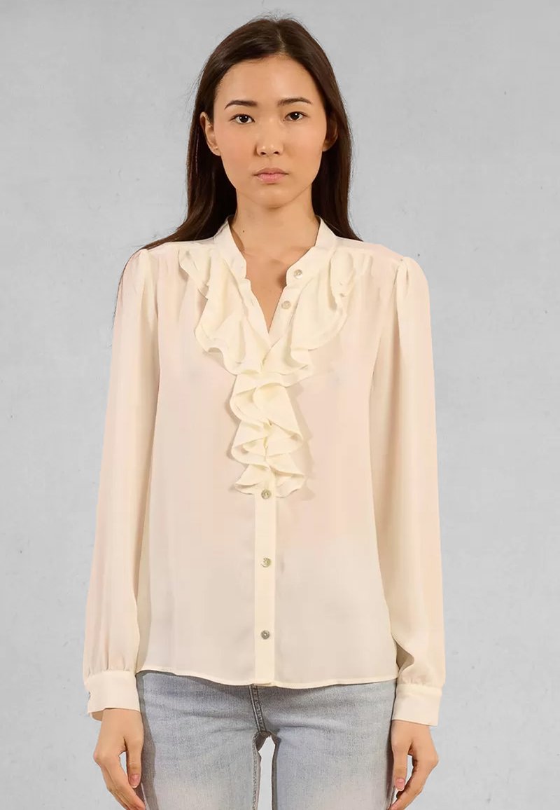 Blusa a maniche lunghe di colore avorio con un davanti arricciato, consistenza morbida e chiusura a bottoni. Tessuto leggero, spalle leggermente arricciate e orlo arrotondato.