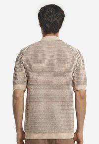 Sweter z krótkim rękawem, teksturowany, w kolorze beżowym z poziomymi paskami. Posiada prążkowany kołnierz i mankiety. Lekki materiał.