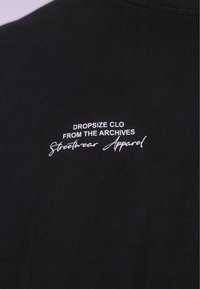 Sort bomulds sweatshirt med ribbet tekstur og hvid broderet tekst: "DROPSIZE CLO FRA ARCHIVE Streetwear Tøj."
