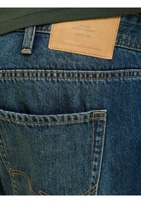 Denim jeans met een blauwe tint, voorzien van een leren label dat op de achterkant is gestikt, met zichtbare stikdetails en een achterzak.