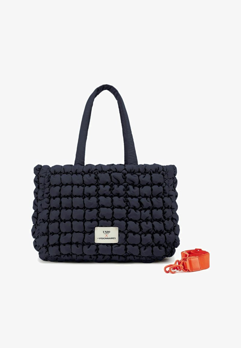Borsa a tote in tessuto trapuntato blu navy con morbide puffer, due manici e una tracolla arancione staccabile. Presenta una patch con il logo sul davanti.