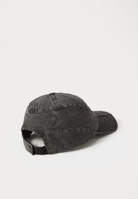 Casquette de baseball en coton noir avec une visière courbée, tissu texturé, couture visible et une sangle réglable à l'arrière.