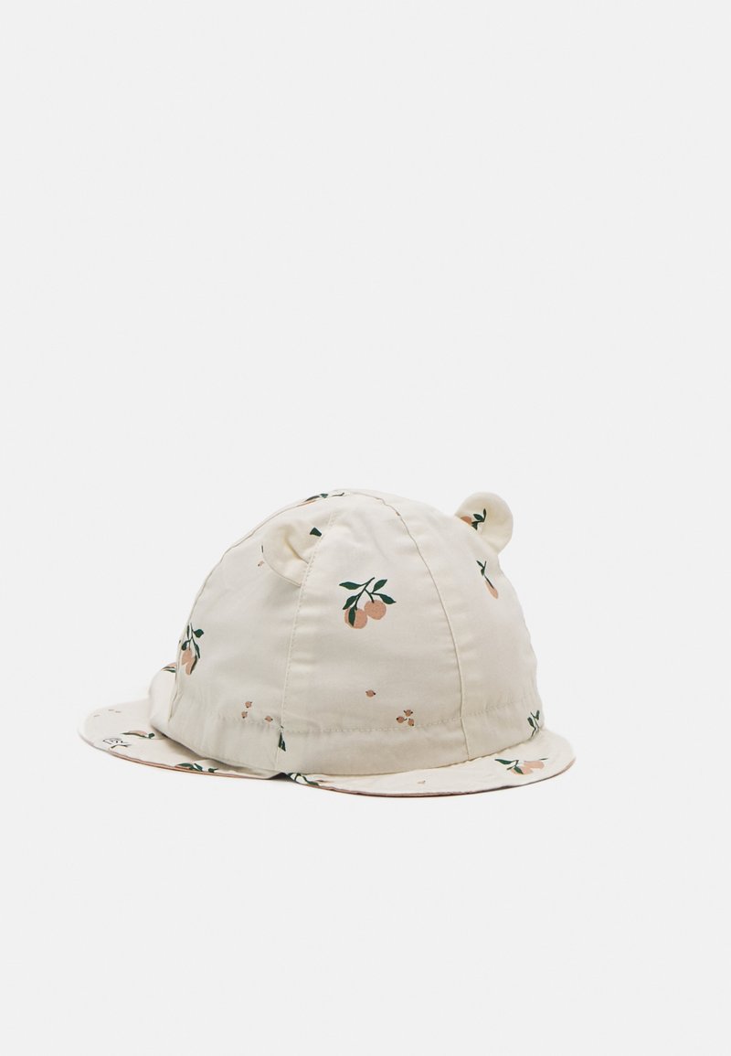 Hette i lys krem med mønster av appelsinblomst, med runde ører, rund krone og buet skjerm med blomsterdetaljer.