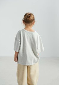 Grå bomulds-T-shirt med løs pasform, rund halsudskæring og korte ærmer, kombineret med beige bukser i blødt, tekstureret stof.