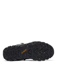La suola delle scarpe outdoor Columbia presenta una superficie in gomma nera texturizzata con macchie multicolori, che offrono aderenza e durata.