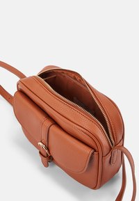 Borsa a tracolla in pelle texturizzata marrone con scomparto principale con zip e tasca frontale, dotata di accessori in oro e tracolla regolabile.