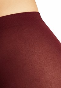 Leggings bordeaux con una texture liscia, caratterizzati da un cinturino alto e un design aderente per comfort e facilità di movimento.