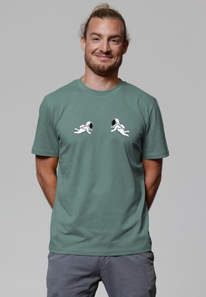 Grünes Baumwoll-T-Shirt mit zwei weißen Astronauten-Grafiken und bunten Akzenten. Rundhalsausschnitt, kurze Ärmel und weicher Stoff.
