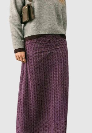 Falda larga morada con estampado, acabado texturizado y detalle fruncido en la cintura, combinada con un suéter gris y un bolso pequeño marrón.