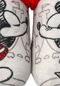 Primer plano de zapatillas blancas con caras de ratones de dibujos animados clásicas bordadas, con acentos de purpurina roja y patrones de líneas abstractas.
