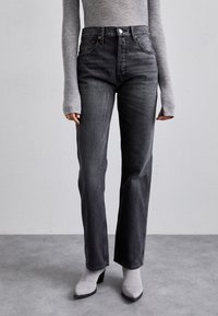Jeans neri a vita alta con taglio dritto, realizzati in denim. Presentano una chiusura anteriore con bottone e dettagli minimi.