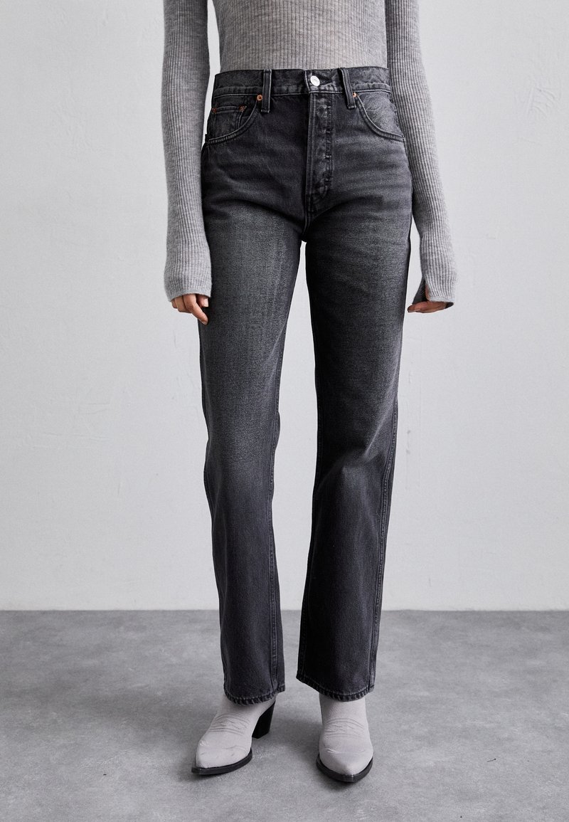 Jeans neri a vita alta con taglio dritto, realizzati in denim. Presentano una chiusura anteriore con bottone e dettagli minimi.