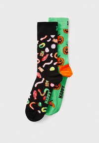 Deux paires de chaussettes : l'une noire avec des motifs colorés de bonbons, l'autre verte avec des citrouilles orange et le texte « HAPPY ». En mélange de coton.