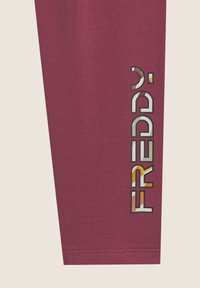 Leggings bordeaux con una superficie liscia presentano un logo laterale con la scritta "FREDDY" in una tipografia multicolore e giocosa.