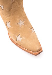 Sandfarbenes Wildleder-Cowboystiefel mit sternförmigen Ausschnitten und weißen Nähten entlang der spitzen Zehe und der Sohle.