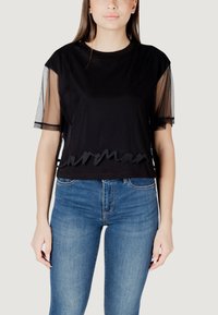 Maglietta nera cropped con maniche corte trasparenti e orlo ricamato a scallop. Indossata con jeans in denim blu aderenti. Design semplice e moderno.