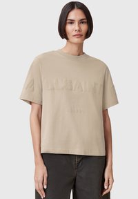 T-shirt in cotone beige con testo in rilievo "ALLSAINTS" e "LONDON" sul davanti, caratterizzato da una vestibilità comoda e maniche corte, design minimalista.